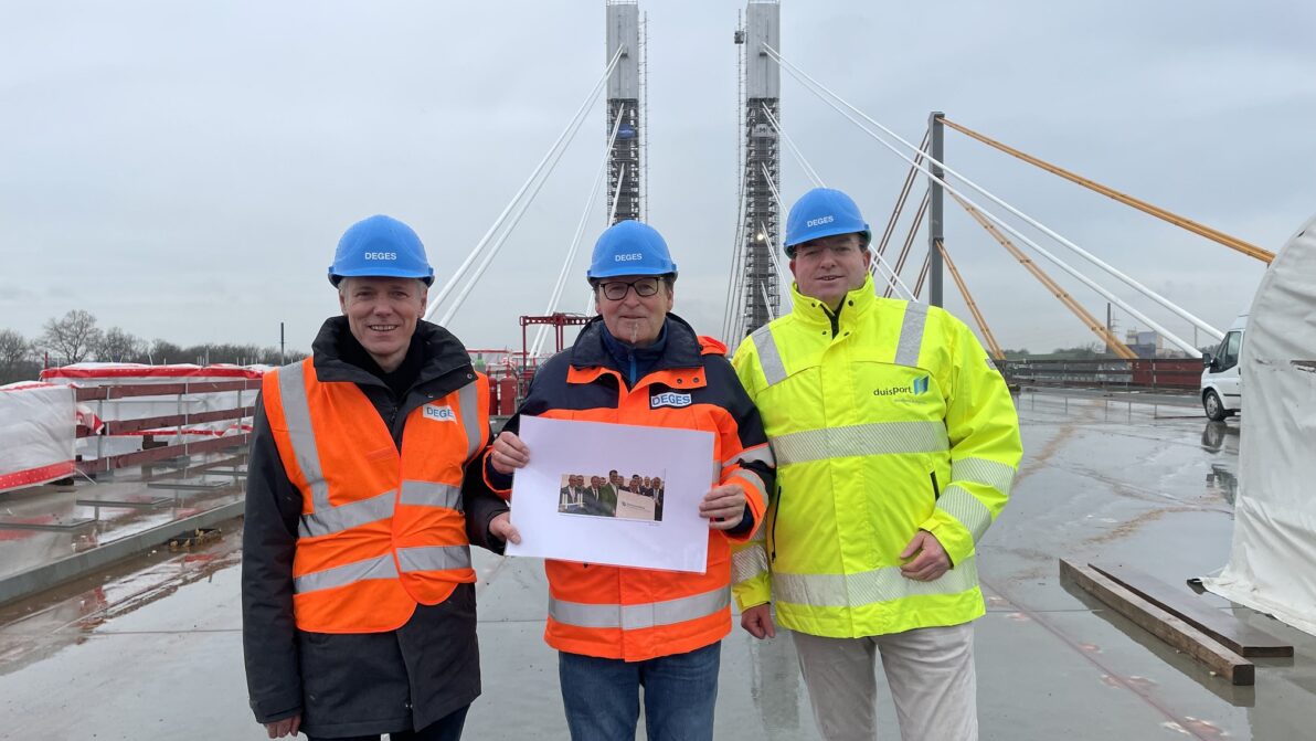 Drei Männer stehen auf einer neuen Autobahnbrücke